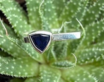 May include: A silver ring with a triangular blue gemstone set in a silver bezel.