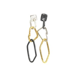 May include: A pair of silver, gold and black geometric earrings with a textured finish. The earrings are made of multiple linked shapes.