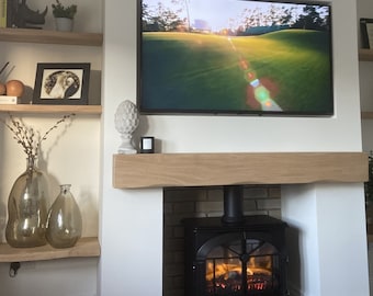 May include: A white fireplace with a black wood-burning stove. The fireplace has a wooden mantel and is decorated with a pine cone, candles, and vases. The stove has a glass door and is lit with flames.