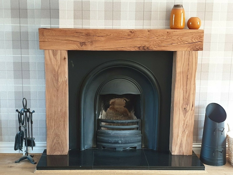 May include: A black fireplace with a wooden mantel and a black hearth. The fireplace has a black metal grate and a black metal firebox. There is a black metal fire poker and shovel set on the hearth.