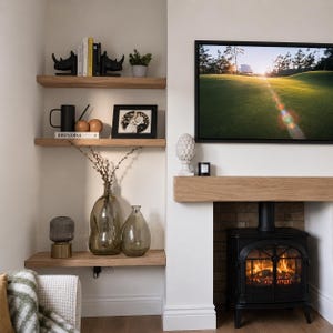May include: A cozy living room corner with wooden shelves displaying decor. Includes black rhino bookends, a framed photo, and a black mug. A fireplace with a lit fire and a TV displaying a golf course scene adds warmth.
