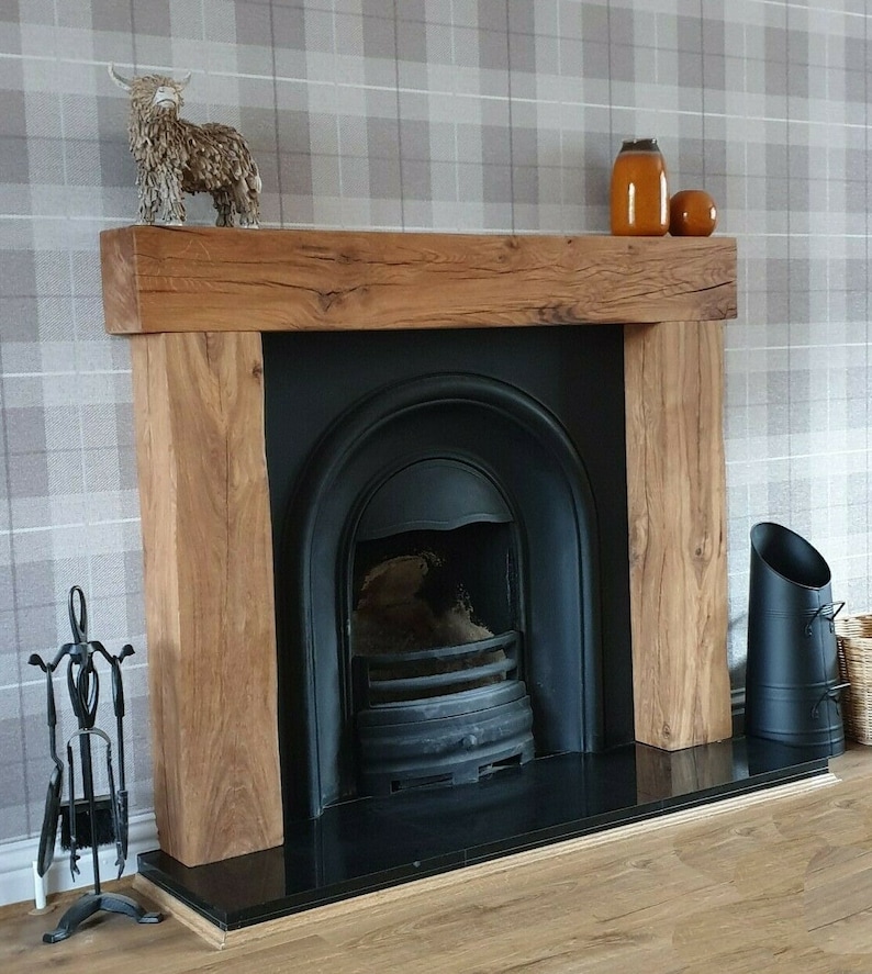 May include: A black fireplace with a wooden mantel and a black hearth. The fireplace has a black metal grate and a black metal firebox. There are two orange ceramic vases on the mantel, and a small brown ceramic animal figurine.