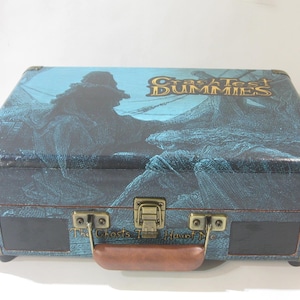 May include: A blue and brown vintage-style record player with a gold handle and metal accents. The top of the record player has a graphic of a ship and the text "Craziest Dummies The Ghosts That Haunt Me".
