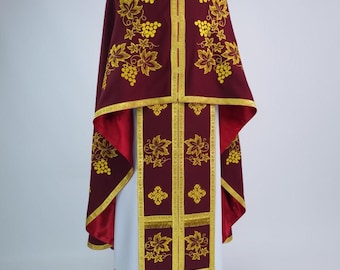 May include: A burgundy religious garment with gold embroidery featuring grape clusters and leaves. The garment has a high collar and gold trim. The undergarment is white. The design is symmetrical and formal.