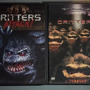 May include: Two DVD cases for the horror movie "Critters." The left case reads "Critters Attack!" in white letters with a monster face. The right case reads "Critters" with a group of monsters. Both cases have dark backgrounds.