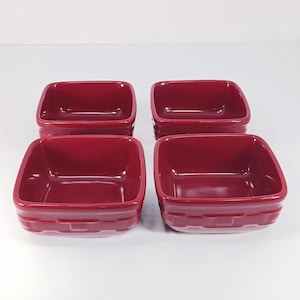 May include: Four square, burgundy-colored ceramic bowls. Each bowl has a slightly textured, ridged design around the base. The bowls are empty and appear to be new. Ideal for serving snacks or small portions.