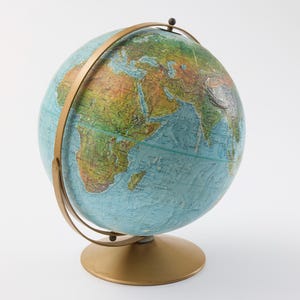May include: A vintage globe with a gold-colored metal stand and meridian. The globe features a detailed map with continents in shades of green, brown, and yellow, and oceans in blue. The globe is a classic educational tool.