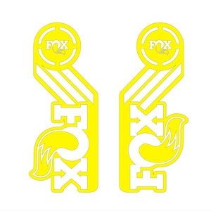 May include: A pair of yellow and white Fox Racing decals with a fox logo and the word "Fox" in a circle. The decals are designed to be placed on a motorcycle or other vehicle.