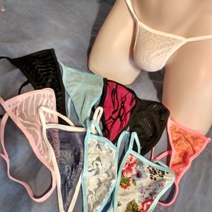 May include: Assortment of colourful lace lingerie with floral and geometric patterns. The lingerie is arranged on a blue fabric surface.
