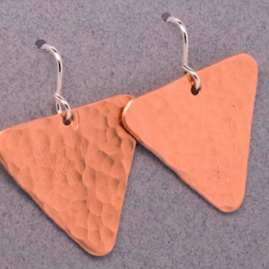 May include: A pair of copper triangle earrings with hammered texture and silver hooks.