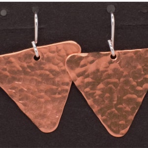 May include: A pair of copper triangle earrings with a hammered texture and silver hooks.