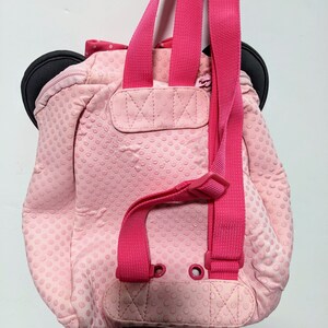 Op de afbeelding: Roze stippenrugzak met zwarte oren en roze banden. De rugzak heeft een klein vakje aan de voorkant.