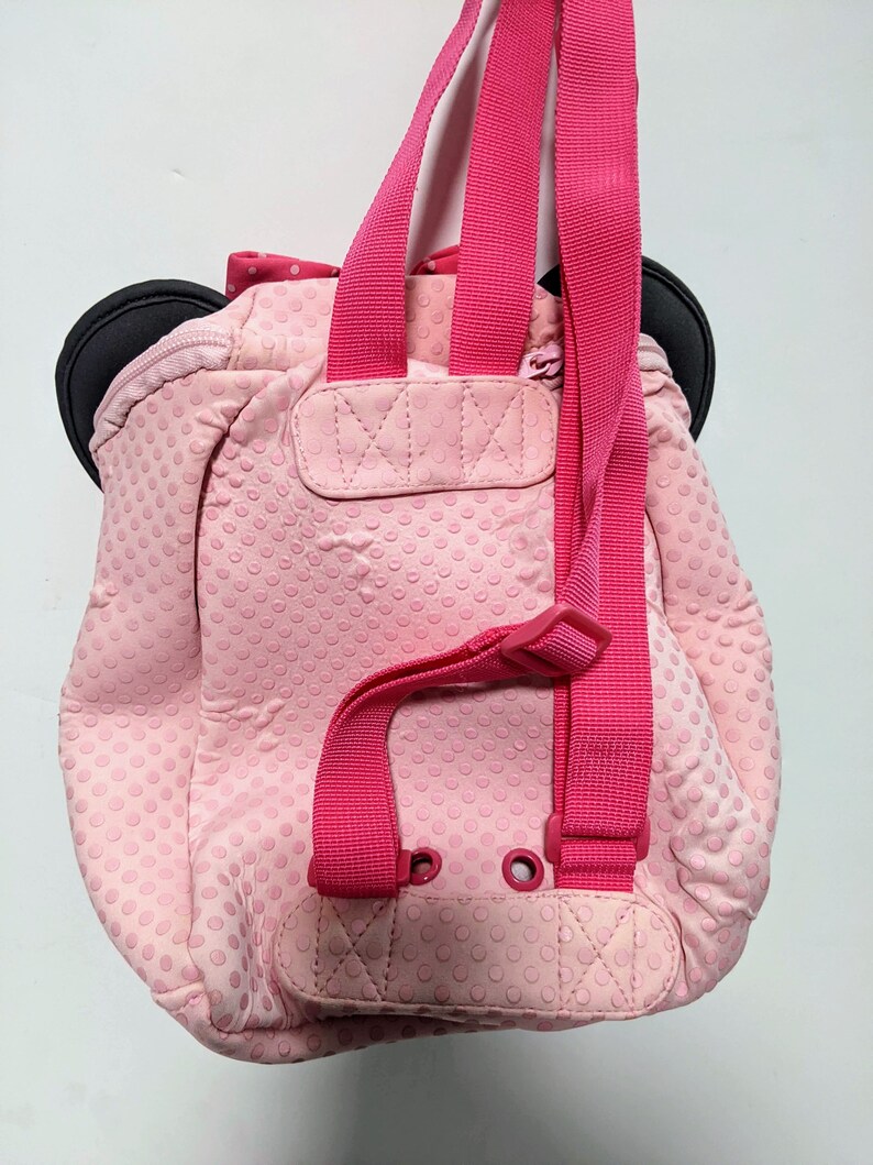 Op de afbeelding: Roze stippenrugzak met zwarte oren en roze banden. De rugzak heeft een klein vakje aan de voorkant.