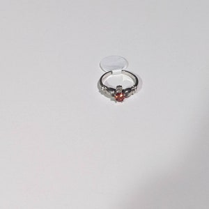 May include: A silver ring with a red gemstone and a Celtic knot design.