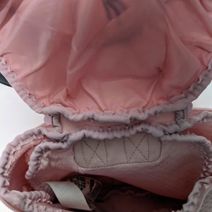 Op de afbeelding: Een roze trekkoordtas met een mesh voering. De tas is open en de voering is zichtbaar. De tas heeft een wit label met zwarte tekst.