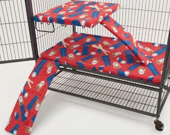 May include: A red fabric cage liner set for small animals featuring a baseball-themed pattern with gloves, bats, and balls. The set includes a rectangular base cover, a raised platform cover, and two ramps, all designed to fit a wire cage.