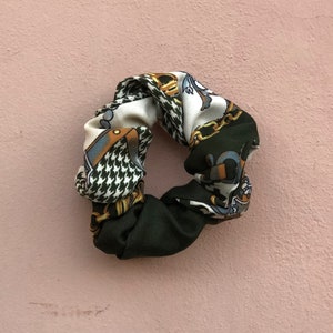 May include: A green and white patterned hair scrunchie with a gold chain design.