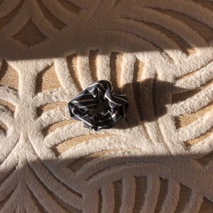 May include: A black and white striped scrunchie on a white fluffy rug with a patterned design.