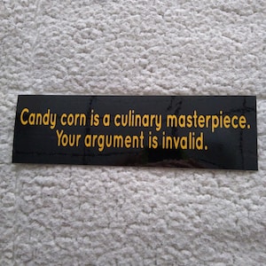 May include: A black rectangular sticker with yellow text that reads: "Candy corn is a culinary masterpiece. Your argument is invalid."