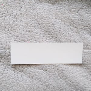 May include: A white rectangular sticker with a smooth surface.