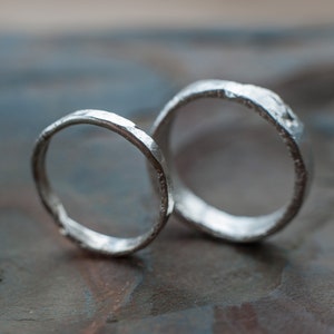 May include: Two silver rings with a textured, hammered finish. The rings are stacked on top of each other.