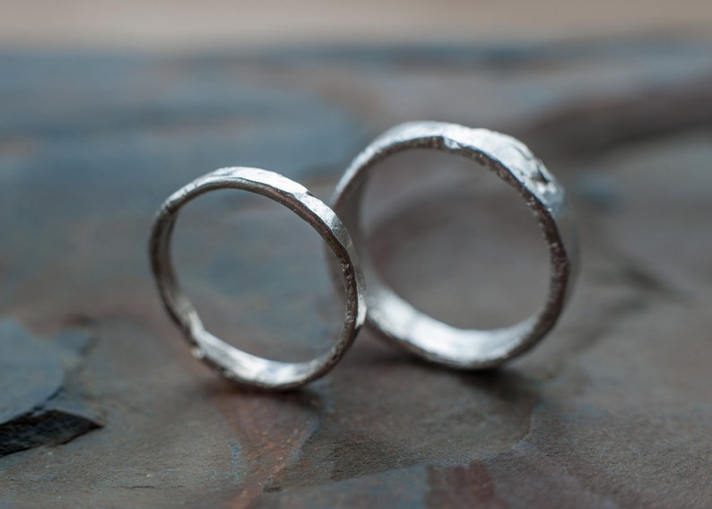 May include: Two silver rings with a textured, hammered finish. The rings are stacked on top of each other.