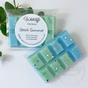 May include: A blue and green wax melt bar with a white label that says "Whitcliffe Aromas Greek Summer 100% Soy Wax Hand Poured in Yorkshire www.whitcliffe aromas.co.uk"