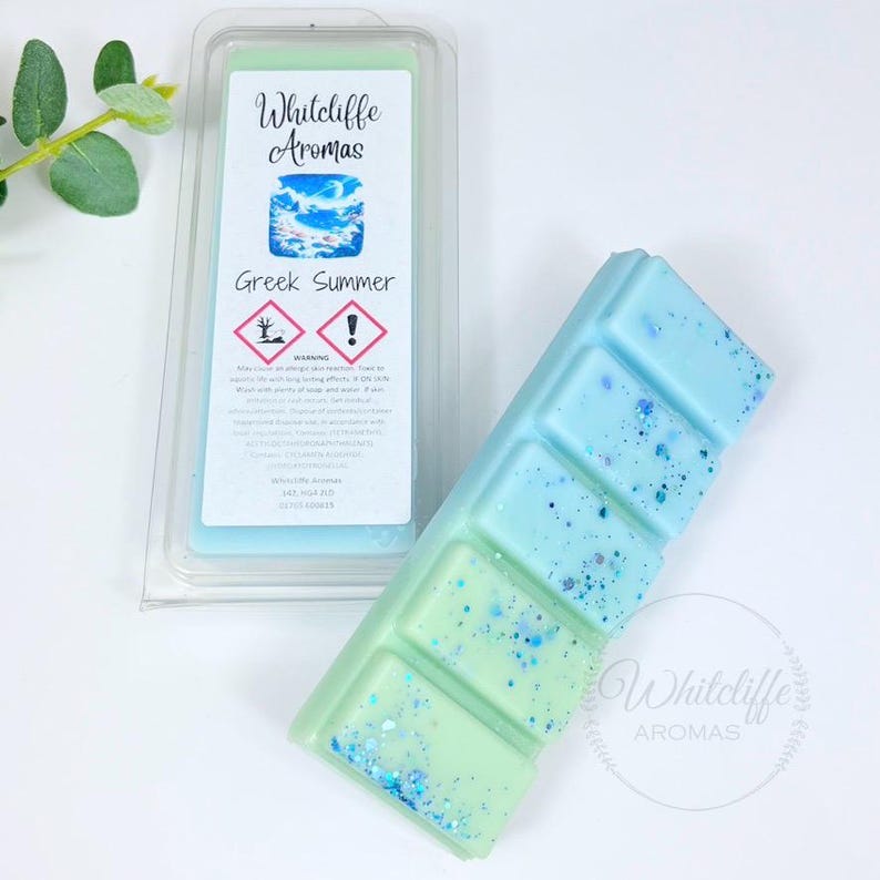 May include: A blue and green wax melt bar with glitter, labeled "Whitecliffe Aromas" and "Greek Summer".