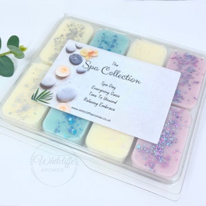 May include: A clear plastic container with 10 wax melts in various pastel colours. The wax melts are decorated with glitter. The container has a white label with the text "The Spa Collection" and "Spa Day Energising Oasis Time To Unwind Relaxing Embrace" and a website address.