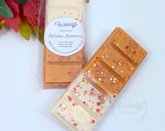 May include: Two wax melt bars, one in a clear package, and one loose. The bars are a mix of cream and orange, with glitter accents. The packaging has a label that reads "Golden Autumn" and "Whitcliffe Aromas."
