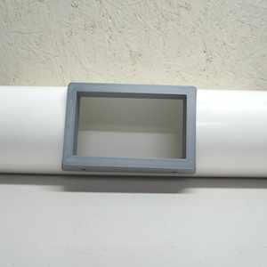 May include: A white cylindrical object with black end caps and a gray rectangular cutout in the center.