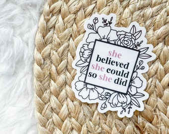 Puede incluir: Una pegatina blanca con ilustraciones florales negras y el texto "She believed she could so she did" en un cuadro negro con fondo rosa.