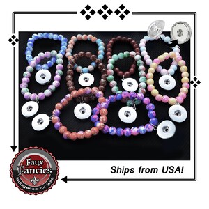 May include: A collection of circular bracelets made from multicolored, marbled beads, each featuring a silver-toned metal snap button attachment. The bracelets display various color combinations including blue, purple, brown, green, pink, and yellow hues.