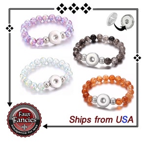 May include: Three snap button bracelets with different colored beads. The bracelets are made with clear beads with flecks of color, including purple, gray, and orange. The snap button is silver.