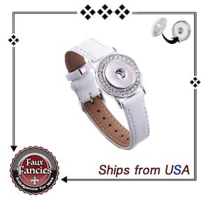 Puede incluir: Reloj de cuero blanco con un botón a presión plateado y detalles de diamantes de imitación. El botón a presión está abierto para mostrar el interior del reloj.