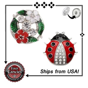 May include: Two decorative snap buttons. One is a silver floral design with red and white flowers, green leaves, and clear crystal accents. The other is a red ladybird with black spots and crystal embellishments.