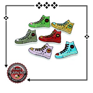 May include: A collection of colorful, high-top sneaker-shaped embellishments. The sneakers are in various colors, including green, yellow, red, purple, and blue, each with a heart detail. The image includes the text "Faux Fancies We Stand Together."