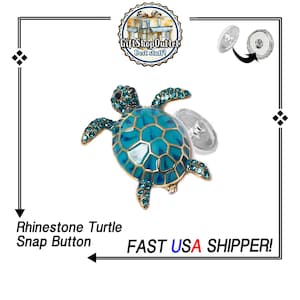 May include: A rhinestone turtle snap button with a turquoise body and gold trim. The turtle has a detailed design with sparkling rhinestones. The text "GiftShopOutlet Best stuff!" is in the upper center.
