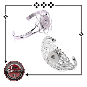 May include: Two silver snap bracelet charms with intricate floral designs. Each charm has a round snap opening for adding a decorative button.