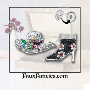 May include: Two rhinestone brooches, one shaped like a hat with colorful flowers and the other shaped like a high-heeled shoe with black and white rhinestones. Both brooches have a silver metal base and are attached to a pin with a magnetic closure.