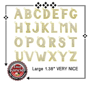 May include: A collection of gold-toned metal alphabet letter charms, each encrusted with clear white rhinestones and featuring a small jump ring at the top. The letters A through Z are displayed in a grid, with the text Large 1.38" VERY NICE.