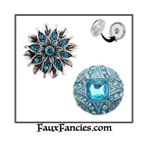May include: Two turquoise blue rhinestone snap buttons with silver settings. One button features a flower design and the other has a square-shaped stone in the center. The buttons are shown with the backings removed.