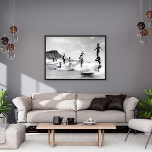 May include: Black and white photograph of a group of people surfing on a beach. The people are standing on surfboards and are in various poses. The photo is framed in a black frame.
