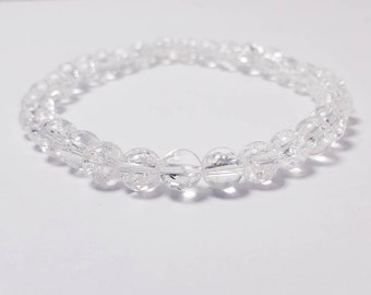 May include: A clear crystal beaded bracelet with a simple design. The bracelet is made of small, round beads that are strung together on a clear elastic cord.