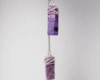 May include: A silver chain necklace with two purple crystal pendants wrapped in silver wire.
