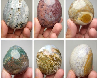 May include: Six smooth, polished, oval-shaped stones with various patterns of brown, white, gray, and pink. The stones are arranged in a grid pattern.