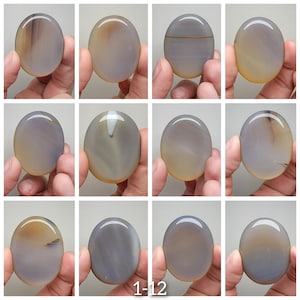 May include: Twelve smooth, oval-shaped agate stones in various shades of gray and brown. The stones are polished and have a natural, organic look.