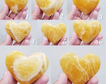 May include: Eight heart-shaped yellow calcite crystals, each with a unique pattern of veins and striations. The crystals are smooth and polished, with a warm, golden hue.