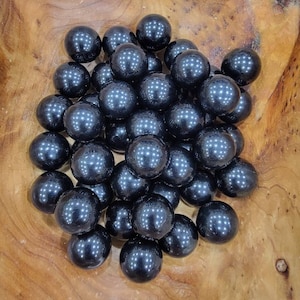 May include: A bowl filled with black obsidian spheres. The spheres are smooth and shiny, and they are arranged in a random pattern.