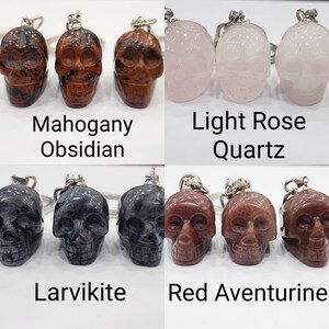 May include: Four sets of three crystal skull keychains. Each set features a different type of crystal: Mahogany Obsidian, Light Rose Quartz, Larvikite, and Red Aventurine.